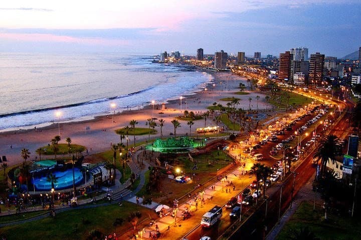 Costanera de Iquique iluminada al atardecer con el mar y la avenida