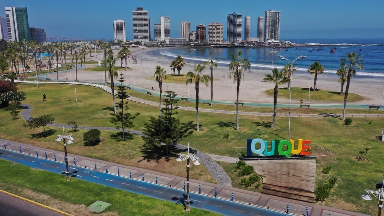 Vista aérea de la costanera de Iquique con el letrero IQUIQUE, la playa Cavancha y el skyline de la ciudad